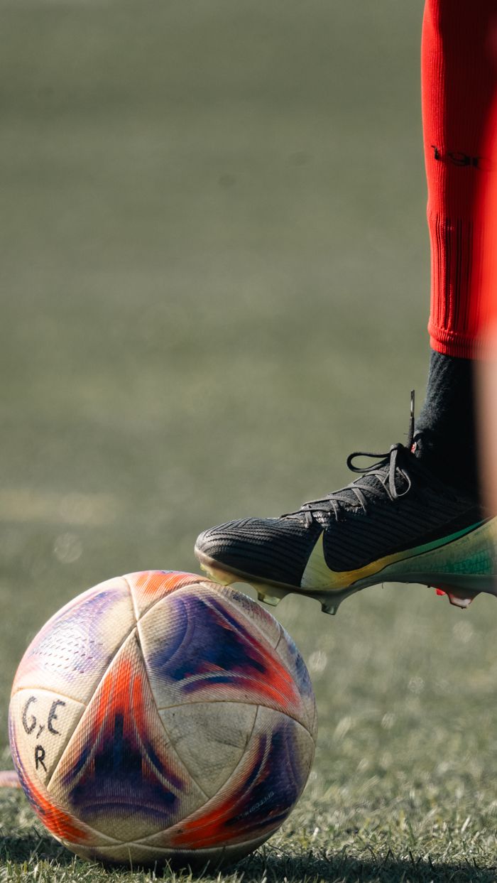 Close-up of a soccer player in red socks preparing to kick a multicolored ball.