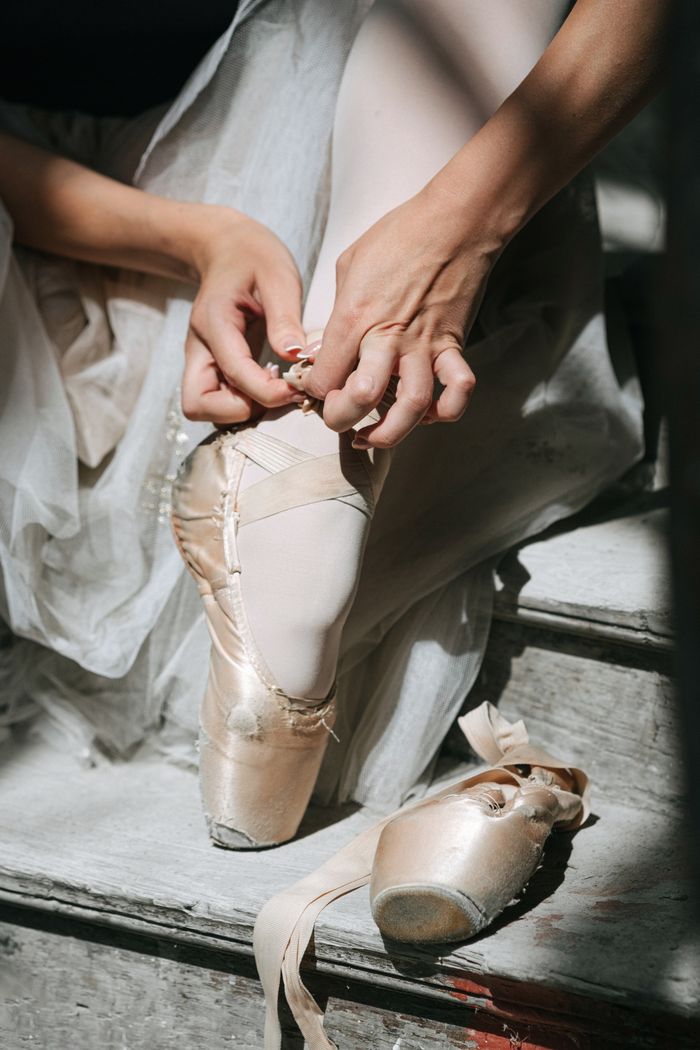 Crafting Captivating Headlines: Your awesome post title goes here Ballerina gracefully tying pointe shoes, capturing elegance and dedication in dance.