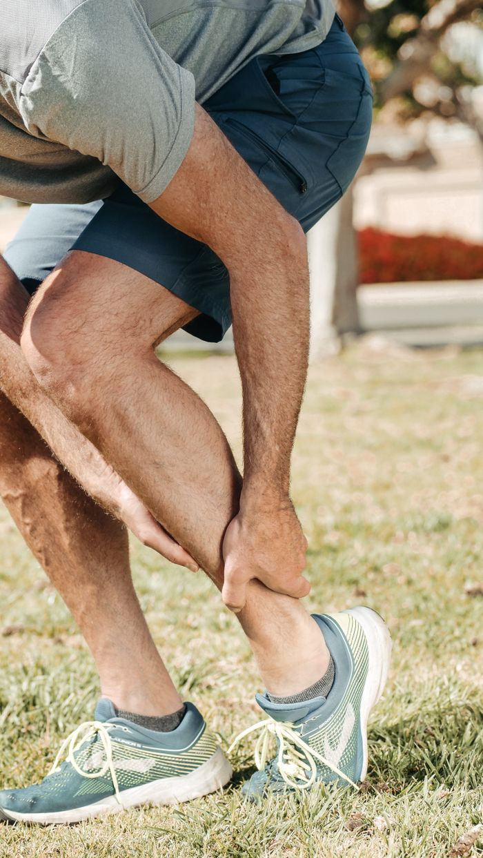 Mastering the First Impression: Your intriguing post title goes here Adult male grabbing ankle due to injury in outdoor setting, wearing rubber running shoes.