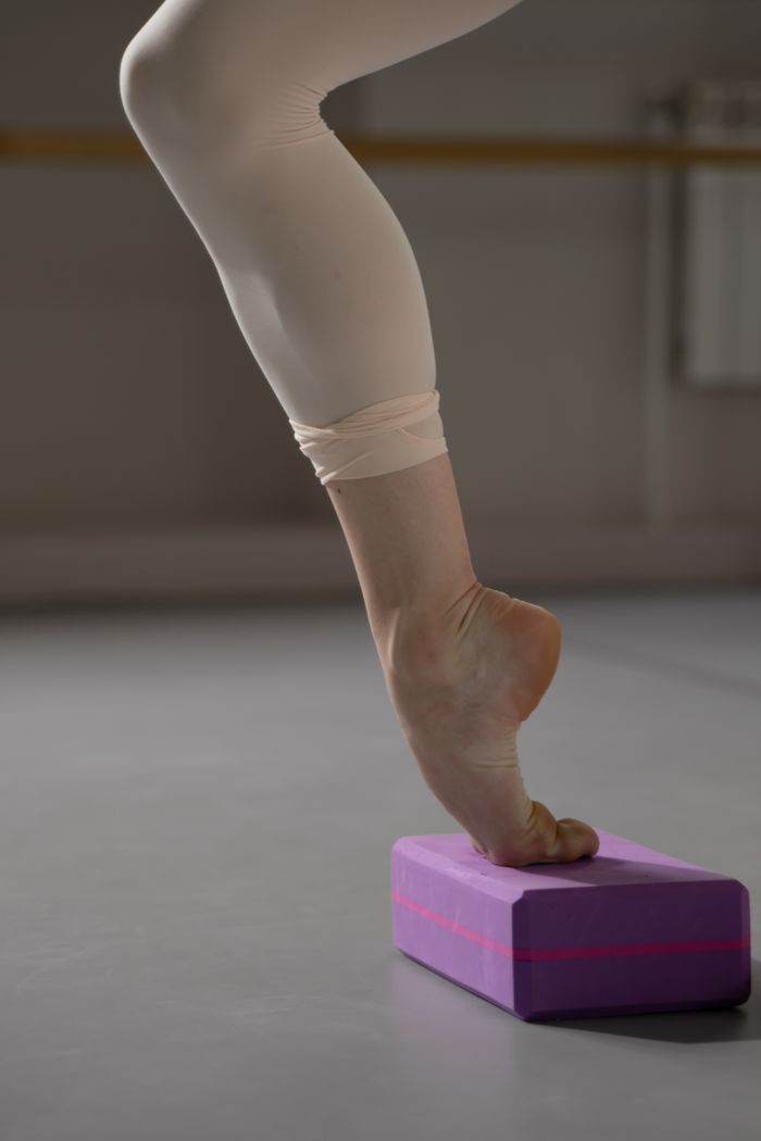 The Art of Drawing Readers In: Your attractive post title goes here A ballet dancer balances gracefully on a yoga block indoors, showcasing flexibility.